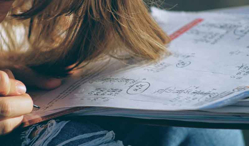 Girl doing maths homework with pencil