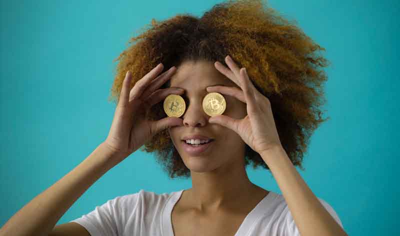 Woman holding two coins in front of her eyes